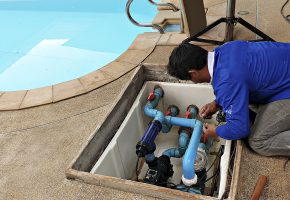 Technician fixing swimming pool water pump. Service and maintenance for swimming pool.